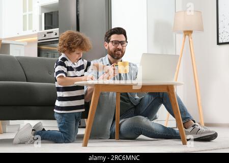 Mann, der zu Hause arbeitet. Vater benutzte Laptop, während sein Sohn am Schreibtisch zeichnete Stockfoto