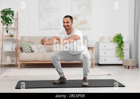 Mann, der zu Hause Morgenübungen auf einer Fitnessmatte macht Stockfoto