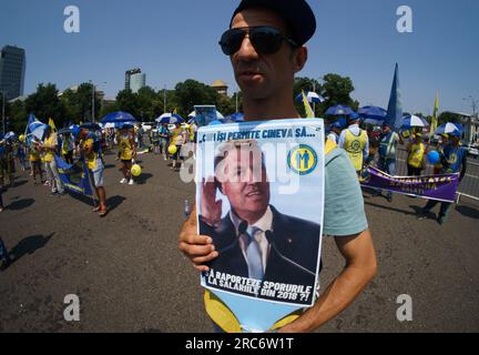 Bukarest, Rumänien. 12. Juli 2023: Ein Protestteilnehmer hält ein Plakat mit dem Bild des rumänischen Präsidenten Klaus Iohannis, der sagt: "Wie kann man sich das leisten..." Bis zu zweitausend Beschäftigte des Gesundheitswesens, Gewerkschafter der rumänischen Föderation "Sanitär-Solidarität", protestieren vor dem Sitz der rumänischen Regierung und fordern höhere Löhne, gewähren alle Rechte, die durch das geltende Gehaltsgesetz, eine faire Verhandlung mit der Regierung, Und die Warnung, dass diese Kundgebung Teil der Protestserie ist, die der Frist für den Generalstreik im öffentlichen Gesundheitssektor vorausgeht. Kredit: Lucian Ale Stockfoto