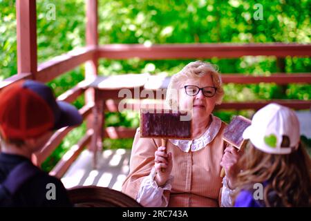 Toronto, Ontario, Kanada - 28. Mai 2023: Eine Seniorin, die Kindern während ihres Besuchs im Pionierdorf Black Creek ein Werkzeug aus dem Jahr 1860er vorstellt. Stockfoto