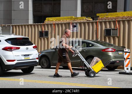 Pittsburgh, Usa. 12. Juli 2023. Ein UPS-Mitarbeiter verwendet einen Handwagen, um Pakete zu transportieren. Der UPS Teamsters-Vertrag für mehr als 340.000 Vollzeit- und Teilzeitmitarbeiter läuft am 31. Juli 2023 aus. Kredit: SOPA Images Limited/Alamy Live News Stockfoto