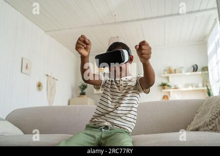 Fokussierter afroamerikanischer Junge fährt Auto und spielt Rennvideospiel in einem Virtual-Reality-Headset. Stockfoto