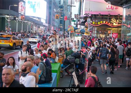 New York City, New York, USA. 12. Juli 2023. Die Menschen fotografieren den Sonnenuntergang an der 42. Street am Times Square an einem der vier Abende des Jahres, die als „Manhattanhenge“ bezeichnet werden, wenn die Sonne perfekt durch Räume zwischen Gebäuden des New York City Street Grid am 12. Juli 2023 in New York City gleitet. Tausende von Touristen und Einheimischen versammeln sich jedes Jahr für die Veranstaltung an Orten, die nach Westen über die Alleen blicken. (Kreditbild: © William Volcov/ZUMA Press Wire) NUR REDAKTIONELLE VERWENDUNG! Nicht für den kommerziellen GEBRAUCH! Stockfoto