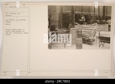Die Bäcker der 339. Bakery Company, die zur 33. Division gehört, werden in Ettlebrick, Luxemburg, gesehen, wie sie Brot in Öfen legen. Dieses Foto wurde von Sergeant Jackson, S.C. aufgenommen, mit den Notizen des Fotografen, die besagen, dass es am 3. Februar 1919 aufgenommen und am 4. Mai 1919 bearbeitet wurde, mit der zugeteilten Nummer E 4-5-19. In den zusätzlichen Hinweisen werden die Referenznummer 1434 und die laufende Nummer 87,901 genannt. Stockfoto