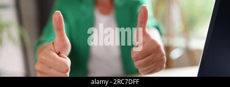 Geschäftsfrau mit Daumen nach oben im Büro und am Tisch mit Computer- und Finanzdokumenten. Stockfoto