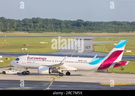 Hamburg, Deutschland. 13. Juli 2023. Klimaschutzaktivisten, die auf einer Rollbahn am Hamburger Flughafen festsitzen, im Vordergrund wird ein Eurowings-Flugzeug verlegt. Eine Gruppe von Klimaaktivisten stieg während einer Aktion auf die Rollbahn des Hamburger Flughafens und steckte sich an zwei Orten fest. Kredit: Bodo Marks/dpa/Alamy Live News Stockfoto