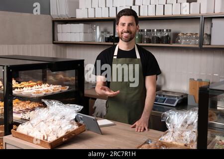 Glücklicher Verkäufer an der Kasse in der Bäckerei Stockfoto
