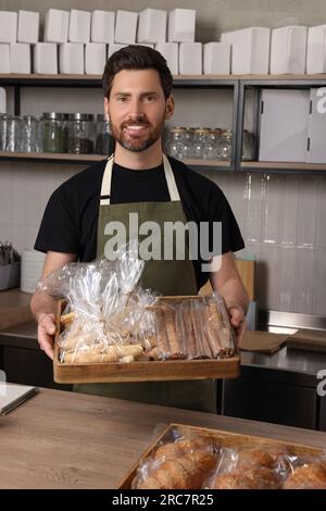 Glücklicher Verkäufer mit Gebäck an der Kasse in der Bäckerei Stockfoto