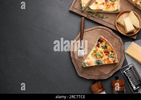 Stücke köstlicher hausgemachter Lachs-Quiche mit Brokkoli, Käse und Gabel auf schwarzem Tisch, flach liegend. Platz für Text Stockfoto