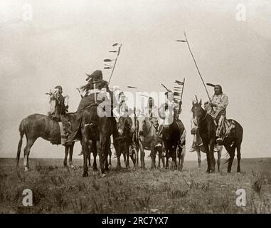 Montana: 1908. Eine Edward S. Curtis Fotogravur von Atsina-Kriegern auf dem Pferderücken. Stockfoto