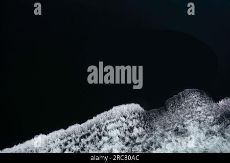 Bogenwellen eines Schiffes mit Schaum auf dem Wasser des Meeres. Spritzwasser. Draufsicht Stockfoto