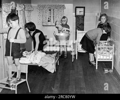 London, England: 24. November 1937 Kinder, die in der Kindertagsklasse an der neuen Middle Park School in Eltham mit Puppen spielen. Stockfoto