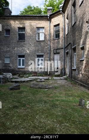 Der Innenhof ist mit Gras überwuchert und verfügt über alte, verfallene Ziegelhäuser in Vilnius, Litauen Stockfoto