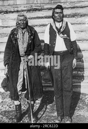 Glacier National Park Reservation, Montana: ca. 1929 Blackfoot Chief Coward und sein Sohn Victor Coward. Der Sohn ist für das fünfjährige Landwirtschaftsprogramm eingeschrieben und bewirtschaftet nun das Land, auf dem sein Vater früher Büffel jagte. Stockfoto