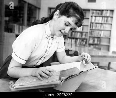 Detroit, Michigan: 30. April 1963 Ein Buchstabierwettbewerber in der siebten Klasse sucht im Wörterbuch nach einem Wort. Stockfoto