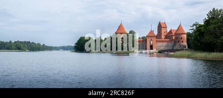 Altes Schloss Trakai mit Ecktürmen, Herzogspalast und hölzerne Fußgängerbrücke auf einer Insel inmitten des Sees Galve in Trakai, Litauen Stockfoto