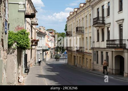 Absteigende Straße in Vilnius mit Fassaden alter historischer Gebäude in Pastelltönen, viele mit Balkon Stockfoto