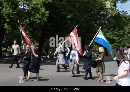 Lettische Nationalisten in Nationalkostümen winken im Zentrum von Riga, Lettland, Flaggen Stockfoto