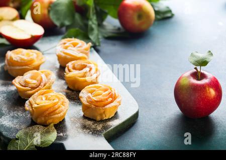 Apfelrosen-Mini-Törtchen mit Puderzucker auf dem Steinschneidbrett. Stockfoto