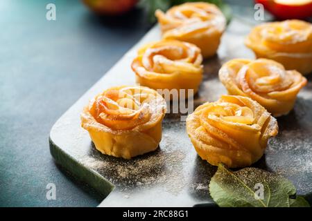 Apfelrosen-Mini-Törtchen mit Puderzucker auf dem Steinschneidbrett. Stockfoto