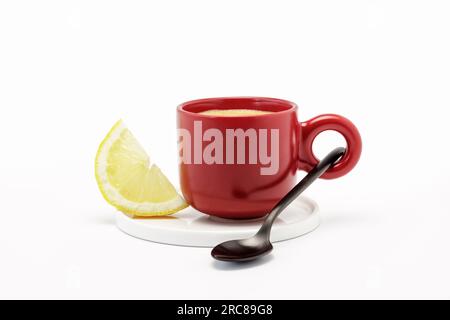 Rote Tasse gefüllt mit starkem Kaffee und einer Scheibe Zitrone, natürliches Kopfschmerzmittel Stockfoto