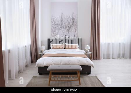 Komfortables Bett und Lampen auf Nachttischen in einem hellen, geräumigen Zimmer. Stilvolle Innenausstattung Stockfoto