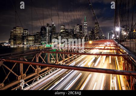 Die Skyline von Manhattan in New York von der Brooklyn Bridge aus, die die beeindruckende Architektur und das moderne Stadtbild bei Nacht zeigt Stockfoto