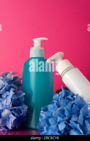 Eine Flasche Feuchtigkeitscreme und Blume auf pinkfarbenem Hintergrund Stockfoto