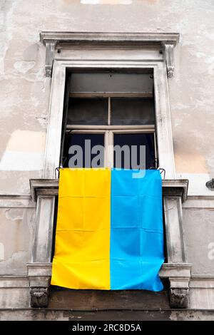 Die ukrainische Flagge hängt aus einem Fenster in Padua, Italien. Unterstützung des ukrainischen Volkes gegen den russischen Angriff. Stockfoto