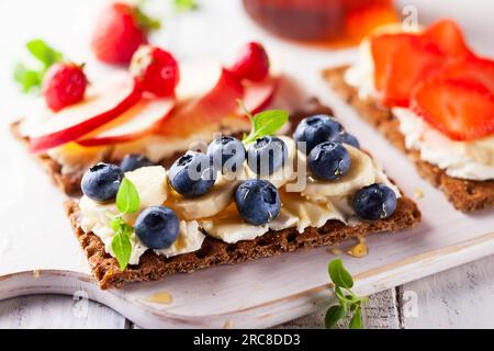 Gesunde Sandwiches mit Beeren, Honig und Frischkäse auf weißem Holzschwein Stockfoto
