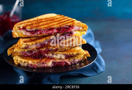 Gegrillte Sandwiches mit Käse, Schinken und Cranberry-Chutney auf dem Teller. Perfekt für das Weihnachtsessen. Stockfoto