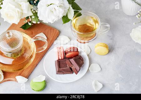 Ästhetische Tischeinstellung. Grüner Tee, Desserts, weißer Bouquet - Zeit für sich selbst, gemütliches Hauskonzept Stockfoto