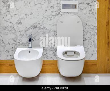 Wandmontiertes weißes Keramikbidet und Toilettenschüssel im Marmorbad Stockfoto