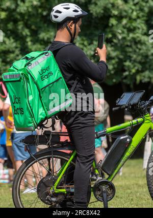 Uber isst einen Liefermann mit Fahrrad, der sein Handy überprüft. Stockfoto