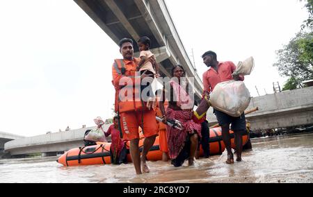 Neu-Delhi, Indien. 12. Juli 2023. Mitglieder der National Disaster Response Force (NDRF) helfen Menschen bei der Evakuierung aus tief liegenden Gebieten, nachdem der Fluss Yamuna aufgrund von unaufhörlichen Regenfällen in Ost-Delhi (Indien) am 12. Juli 2023 angeschwollen war. Kredit: Str/Xinhua/Alamy Live News Stockfoto