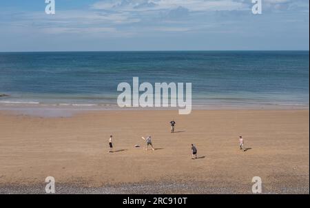 Fünf junge Männer spielen Cricket am Strand bei Ebbe in Sheringham, Norfolk. Stockfoto