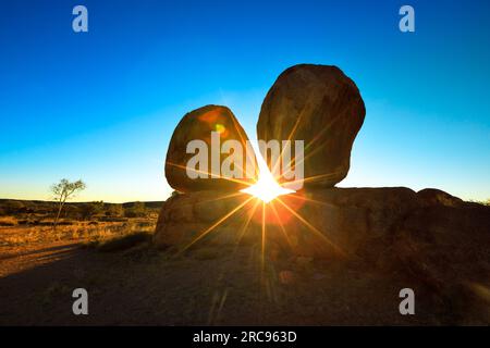 Sonnenstrahlen in der Dämmerung hinter iconic Devils Marbles: Eier von mythischen Regenbogenschlange. Karlu Karlu Devils Marbles Conservation Reserve ist einer von Australiens Stockfoto