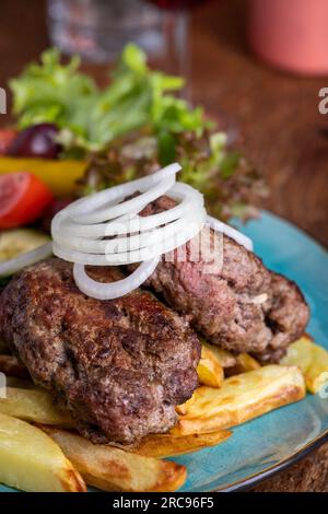 griechischer Bifteki mit Salat und Pommes frites Stockfoto