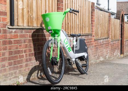 LONDON, Vereinigtes Königreich - 13. JULI 2023: Ein Lime-Leihfahrrad, das vor einem Zaun in einem Wohngebiet von London abgestellt wurde Stockfoto