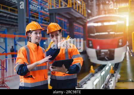 Ingenieurarbeiter und -innen arbeiten zusammen im elektrischen Bahndienstdepot Transportindustrie Werkstechniker Mitarbeiter. Stockfoto