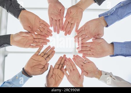 Junge Freiwillige legen ihre Hände wie ein echtes Team aufeinander, während sie im Büro einer Wohltätigkeitsorganisation stehen Stockfoto