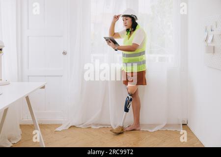 Professionelle Hausbauerin Behinderteningenieurin Frau mit Prothesen Bein intelligent arbeitendes Haus renovieren mit Sicherheit Stockfoto