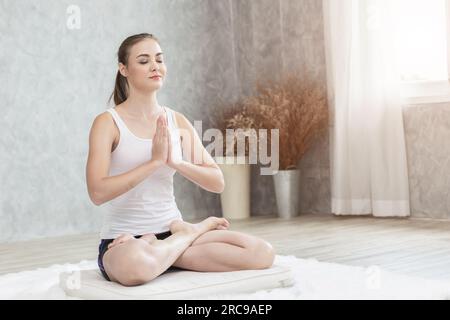 Schöne Frau Yoga in Padmasana Meditation Pose zu Hause Stockfoto