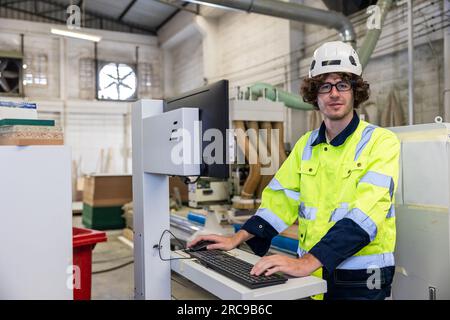 Junger weißer Ingenieur, männlicher Angestellter, der in einer modernen Möbelfabrik lächelt Stockfoto