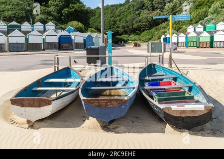 Middle Chine, Bournemouth, Großbritannien - Juli 12. 2023: Drei Ruderboote am Strand vor Strandhütten. Stockfoto