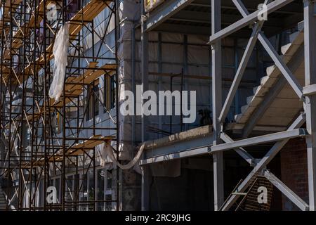 Bau eines Gebäudes unter Verwendung von Gerüsten. Renovierungsarbeiten an der Fassade. Gerüstfragment und Treppe gegen die Hauswand. Sicherheit am Konstrukt Stockfoto