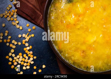 Leckere heiße Erbsensuppe und Zwiebeln serviert mit Scheiben Brot Stockfoto