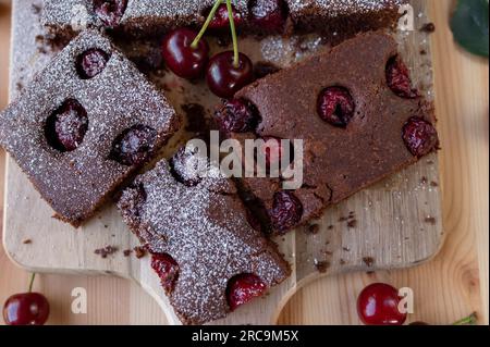 Schokoladenkuchen mit Sauerkirschen auf einem hellen Holztisch. Draufsicht Stockfoto