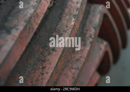 Nahaufnahme und Detailansicht einer roten spiralverzahnten Welle. Industrielle Geschichtsmaschine. Eisen- und Stahlproduktion. Stockfoto