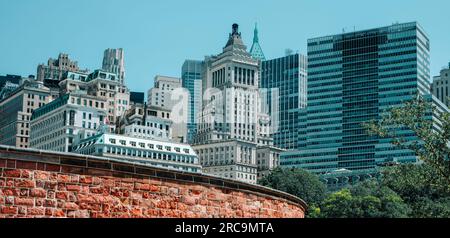 Ein Blick auf die Skyline von Lower Manhattan in New York City, USA, seit Battery Park, mit Castle Clinton im Vordergrund, in einem Panoramablick f Stockfoto